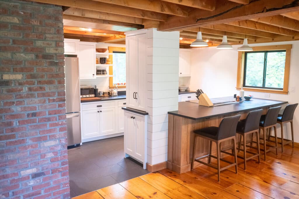 Design-build team discussing kitchen layout plans with homeowner in a cozy, light-filled Vermont kitchen